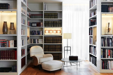 Immagine di un piccolo soggiorno minimal con libreria, pareti bianche, pavimento in legno massello medio e pavimento marrone