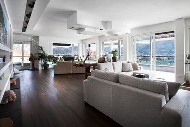 Immagine di un grande soggiorno design con pareti bianche, parquet scuro, cornice del camino in pietra, TV a parete e pavimento marrone