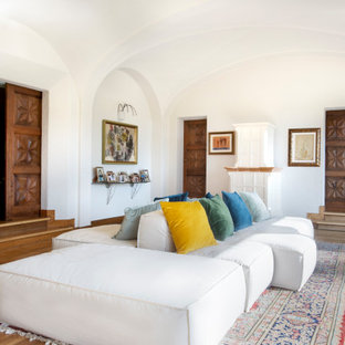 Idee per un ampio soggiorno mediterraneo aperto con parquet chiaro, cornice del camino in legno, nessuna TV, pavimento beige, soffitto a volta e pareti bianche