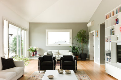 Idées déco pour une grande salle de séjour moderne avec parquet clair, un téléviseur fixé au mur et un mur gris.
