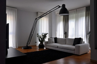 Foto di un soggiorno minimal di medie dimensioni e chiuso con pareti grigie, parquet chiaro, camino classico, cornice del camino in pietra e TV a parete