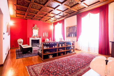 Immagine di un soggiorno tradizionale con pareti rosse, pavimento in legno massello medio, camino classico e cornice del camino in pietra