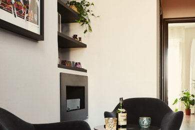 Modelo de sala de estar con barra de bar minimalista con paredes blancas, suelo de madera en tonos medios, chimeneas suspendidas, marco de chimenea de metal y suelo marrón