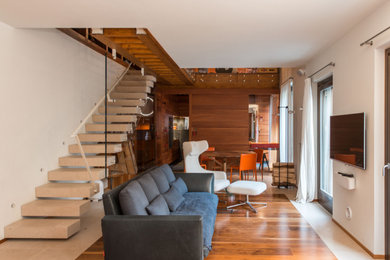 Großes, Abgetrenntes Modernes Wohnzimmer mit weißer Wandfarbe, dunklem Holzboden und TV-Wand in Sonstige