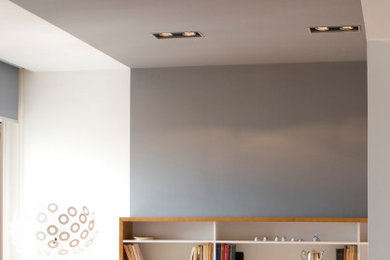 Immagine di un soggiorno moderno con libreria, pareti grigie e parquet chiaro
