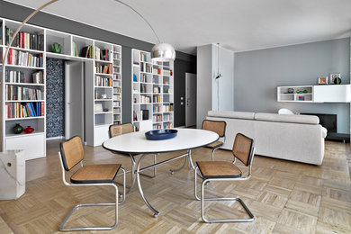 Foto di un soggiorno moderno aperto con pareti grigie, parquet chiaro, TV autoportante e libreria