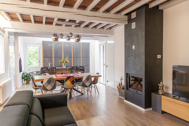 Modelo de salón abierto actual de tamaño medio con paredes blancas, suelo de madera en tonos medios, todas las chimeneas, suelo marrón y televisor independiente
