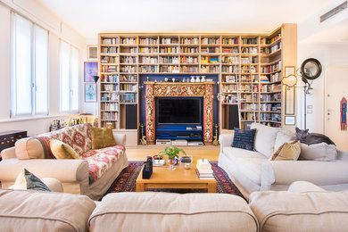 Idee per un grande soggiorno mediterraneo con libreria, pareti blu, parquet chiaro, camino classico, cornice del camino in legno e TV nascosta