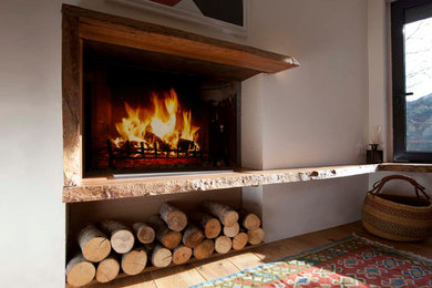 Example of a mountain style light wood floor and brown floor living room design in Other with a standard fireplace and a wood fireplace surround