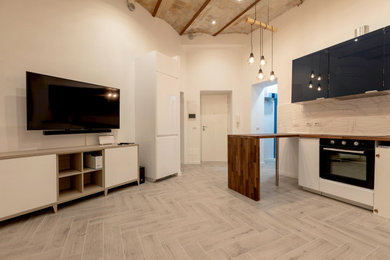 Foto de salón tipo loft urbano pequeño con paredes blancas, suelo de baldosas de porcelana, televisor colgado en la pared y suelo beige