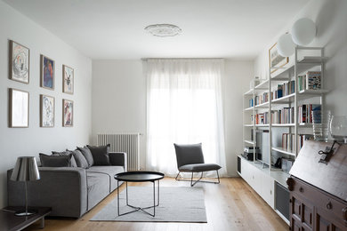 Diseño de biblioteca en casa abierta escandinava de tamaño medio sin chimenea con paredes blancas, suelo de madera en tonos medios, pared multimedia y suelo marrón