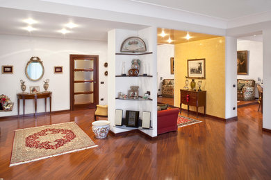 Imagen de sala de estar abierta ecléctica grande con paredes blancas y suelo de madera en tonos medios