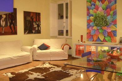 Idee per un soggiorno contemporaneo con libreria, pareti gialle, parquet chiaro e TV a parete