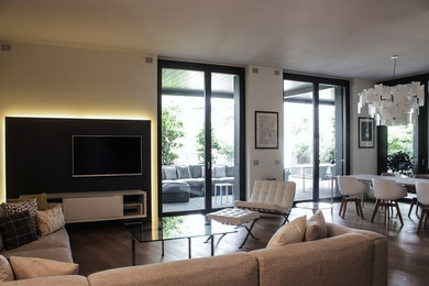 Foto de sala de estar abierta contemporánea de tamaño medio con paredes blancas, suelo de madera oscura y televisor colgado en la pared