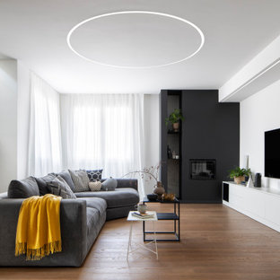 Ispirazione per un grande soggiorno design aperto con pareti bianche, parquet scuro, camino classico, cornice del camino in intonaco, TV a parete e pavimento marrone