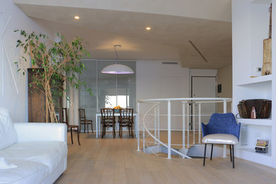 Immagine di un grande soggiorno moderno aperto con libreria, pareti beige e parquet chiaro