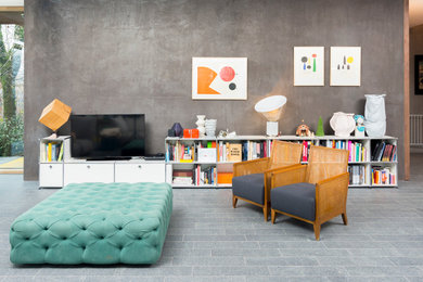 Aménagement d'une salle de séjour éclectique de taille moyenne et ouverte avec une bibliothèque ou un coin lecture, un mur gris, un téléviseur indépendant, un sol en calcaire et un sol gris.