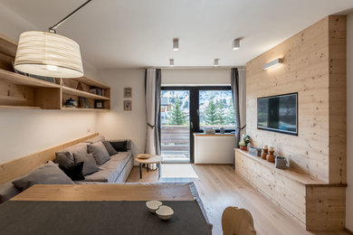 Idee per un soggiorno design con pareti bianche, parquet chiaro, TV a parete e pavimento beige