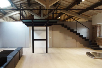 Inspiration för ett mellanstort industriellt loftrum, med grå väggar, ljust trägolv och en spiselkrans i metall