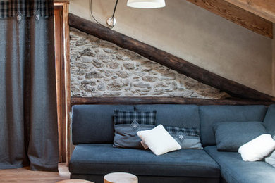Immagine di un grande soggiorno stile rurale aperto con camino bifacciale, TV a parete, pareti beige, pavimento in legno massello medio e cornice del camino in legno