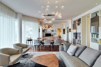 Cette image montre un grand salon design ouvert avec une bibliothèque ou un coin lecture, un mur blanc, un sol en bois brun, un téléviseur indépendant et un sol marron.