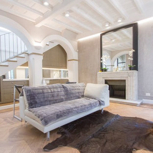 Esempio di un piccolo soggiorno design aperto con pareti grigie, parquet chiaro, camino classico, cornice del camino in pietra, pavimento beige e TV a parete