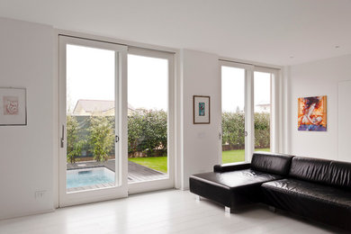 Idee per un soggiorno minimalista con pareti bianche e parquet chiaro