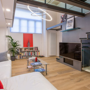 Foto di un soggiorno design aperto con pareti grigie, pavimento in legno massello medio, TV a parete e pavimento marrone