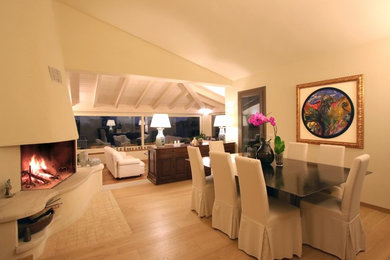 Foto di un soggiorno minimalista di medie dimensioni con pareti beige, parquet chiaro, camino ad angolo e cornice del camino in intonaco