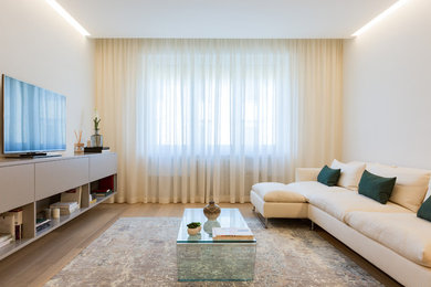 Immagine di un soggiorno design con pavimento in legno massello medio, TV autoportante, pareti bianche e pavimento marrone