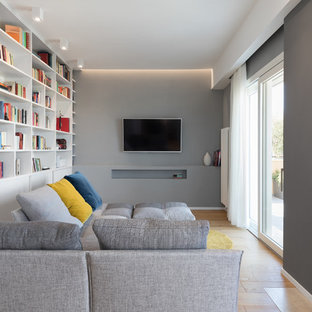 Ispirazione per un soggiorno contemporaneo con libreria, pareti grigie, pavimento in legno massello medio, camino classico, TV a parete e pavimento marrone