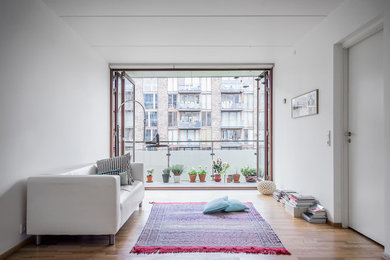 Imagen de sala de estar abierta actual de tamaño medio con paredes blancas y suelo de madera en tonos medios