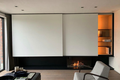 Esempio di un grande soggiorno minimalista aperto con pareti bianche, pavimento in legno verniciato, cornice del camino in legno e TV a parete