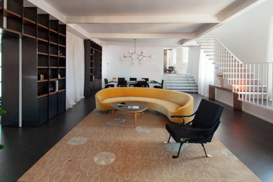 Foto di un soggiorno con libreria, pareti bianche e pavimento nero