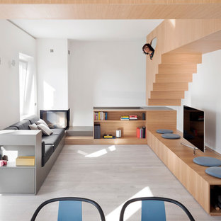 Foto di un soggiorno moderno di medie dimensioni e stile loft con pareti bianche, parquet chiaro, camino ad angolo, cornice del camino in intonaco, pavimento grigio e TV autoportante