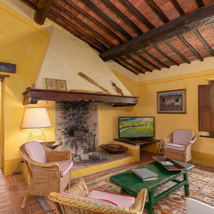 Idee per un soggiorno mediterraneo chiuso con pareti gialle, pavimento in terracotta, TV autoportante e pavimento arancione