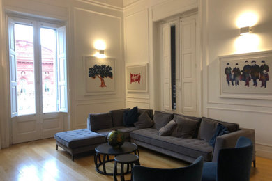 Foto de sala de estar cerrada actual de tamaño medio con paredes blancas, suelo de madera clara y televisor colgado en la pared