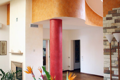 Foto de sala de estar abierta mediterránea grande con paredes multicolor, suelo de madera en tonos medios, chimenea de doble cara y marco de chimenea de yeso