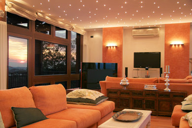 Idee per un grande soggiorno minimalista aperto con pareti arancioni, parquet chiaro, TV autoportante e pavimento marrone