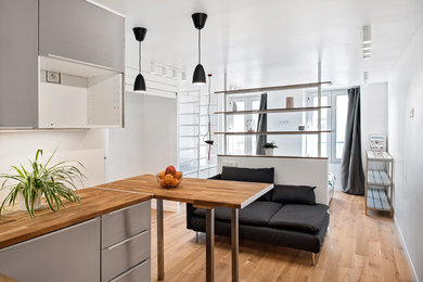 Foto de sala de estar con biblioteca abierta nórdica pequeña con paredes blancas, suelo de madera clara y televisor colgado en la pared