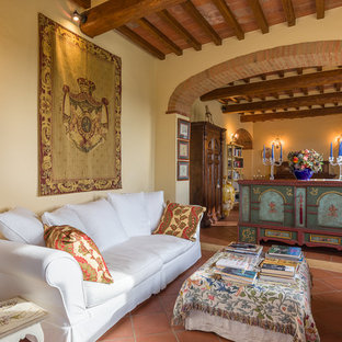 Immagine di un soggiorno mediterraneo con pareti beige, pavimento in terracotta, TV autoportante e pavimento rosso