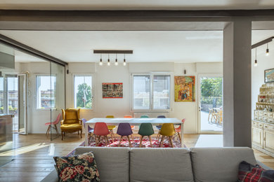 Esempio di un grande soggiorno moderno aperto con pareti bianche, parquet chiaro e TV a parete