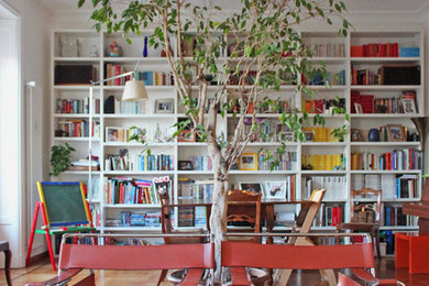 Immagine di un soggiorno moderno di medie dimensioni e aperto con libreria, pareti bianche e parquet chiaro