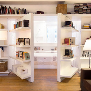 Immagine di un soggiorno contemporaneo chiuso con libreria, pareti bianche e parquet chiaro