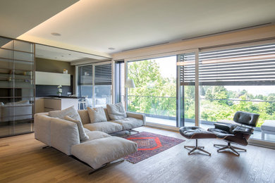 Esempio di un ampio soggiorno minimalista aperto con pareti bianche, pavimento in legno massello medio, nessun camino, TV a parete, pavimento marrone e soffitto ribassato
