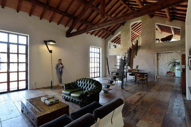 Photo of an industrial open plan living room in Milan with grey walls and medium hardwood flooring.