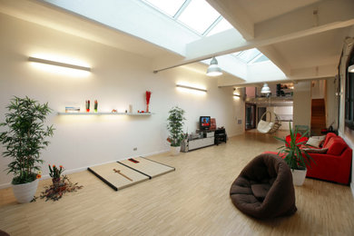 Immagine di un ampio soggiorno eclettico stile loft con pareti bianche, parquet chiaro e travi a vista