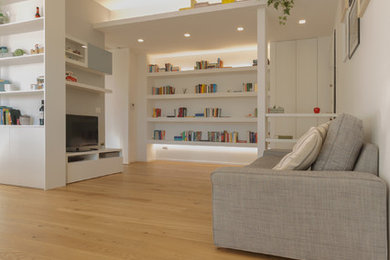 Foto de biblioteca en casa abierta contemporánea de tamaño medio con paredes grises, suelo de madera clara, pared multimedia y suelo beige