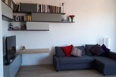 Foto di un soggiorno design di medie dimensioni e aperto con libreria, pareti bianche, parquet chiaro, TV autoportante e pavimento beige