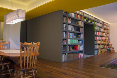 Foto di un grande soggiorno minimal aperto con libreria, pareti grigie, pavimento in legno massello medio e pavimento marrone